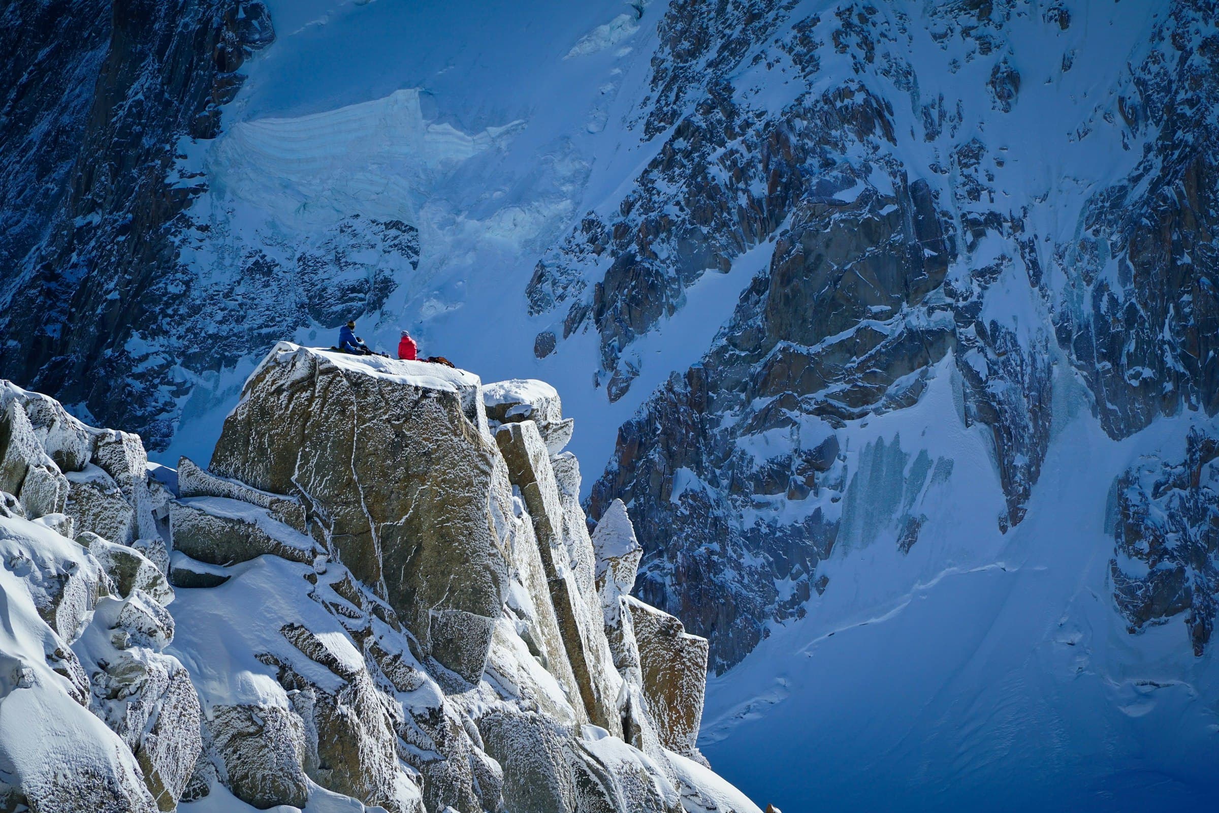 Climbers ascending a snow ridge toward the summit